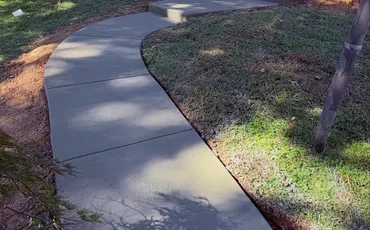 Curved concrete walkway through a front yard