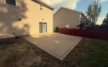 New broom-finish concrete patio behind a two-story home