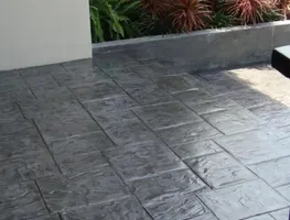 Charcoal stamped concrete with a retaining wall planter