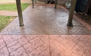 Red stamped concrete patio under a wood pergola